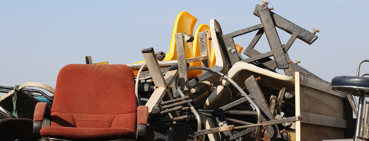 Pile of old chairs and office equipment with blue backdrop