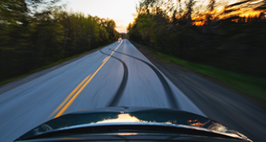 Car tread marks swerving down the road near the forest 