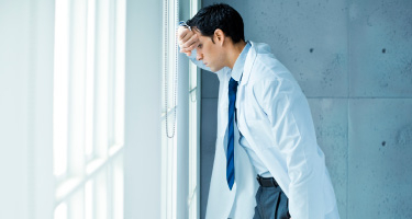 Man stands by building looking exhausted 