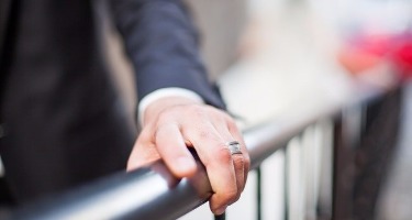 Hand wearing a wedding ring placed on a railing.