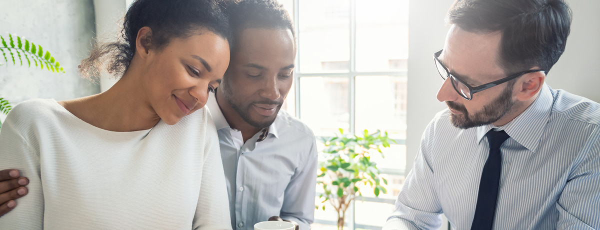 A couple sitting with a real estate attorney reviewing documents for refinancing their mortgage