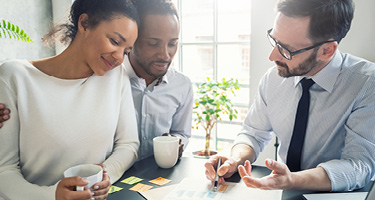 A couple sitting with a real estate attorney reviewing documents for refinancing their mortgage