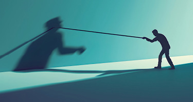 Silhouetted figure has a tug of war with shadow