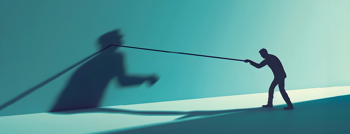 Silhouetted figure has a tug of war with shadow