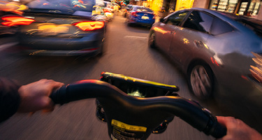 Blurry Cyclist POV Navigating Between Cars on Road