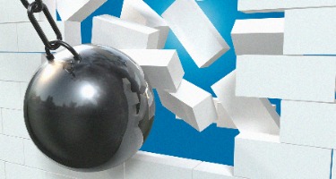 Silver wrecking ball destroying a white brick wall