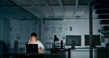 Man in the dark staring at his bright computer screen 