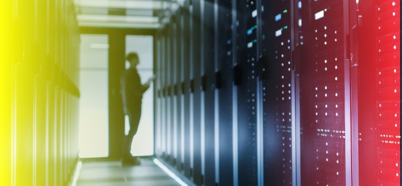 Man blurred fiddles with computer with a long line of computers and a yellow and red filter