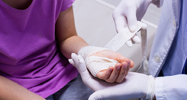 Close-up of a medical professional bandaging a patient’s injured hand