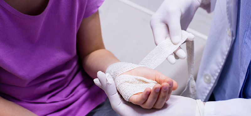 Close-up of a medical professional bandaging a patient’s injured hand