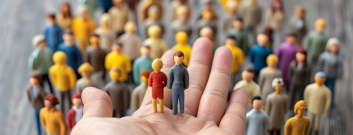 Two toy people being held in the palm of someone's hand above a group of other toy people