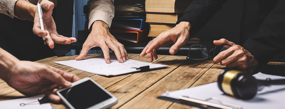 Hands joined around table with phone, paper, pen and glasses