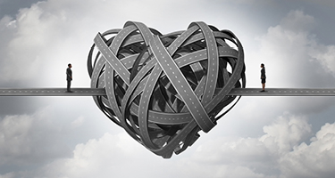 Two people standing on either side of a heart made out of curving roads