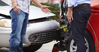 Two individuals standing at the scene of a car accident