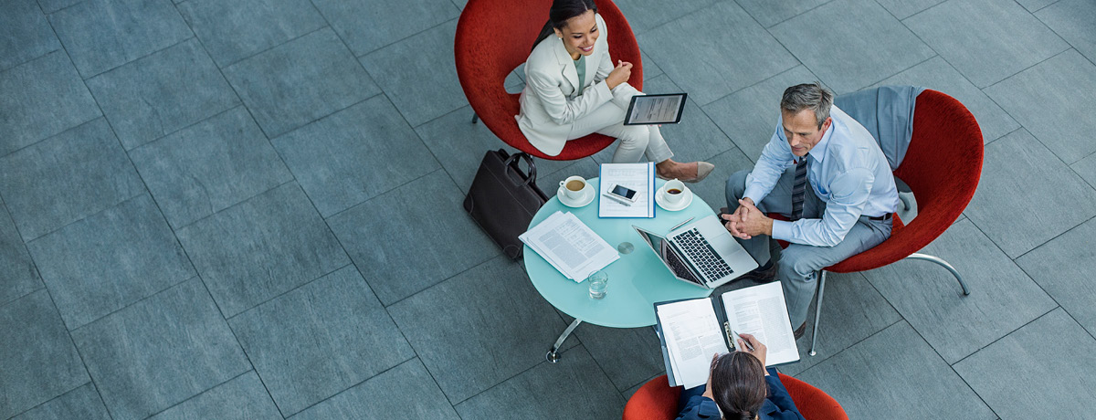 One male and two females working together at table with computer and notebooks