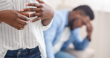 Wife taking off her wedding ring next to her husband going through divorce