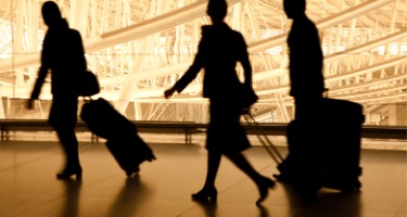 Flight attendants and pilot silhouettes walk in the airport with construction in the back 