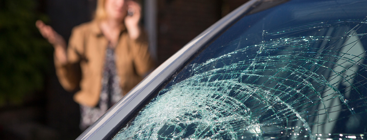 Windshield is cracked with driver in background on phone