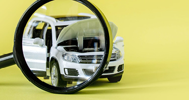 Yellow background with white car being viewed through magnifying glass