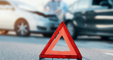Road caution sign in front of two wrecked cars