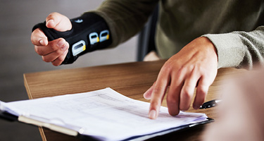 Unseen individual with hand brace points to a legal contract