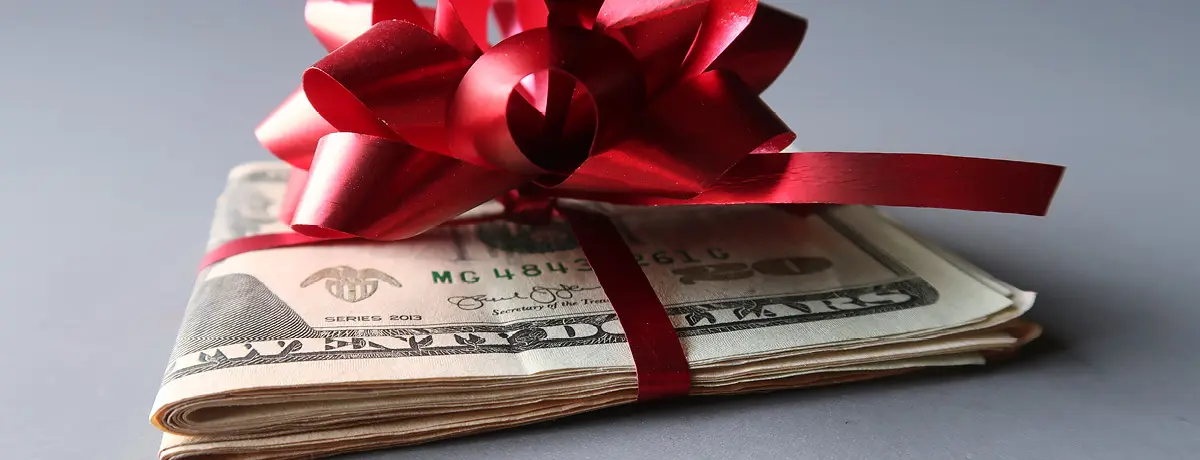 Stack of money wrapped in a festive bow, symbolizing holiday pay