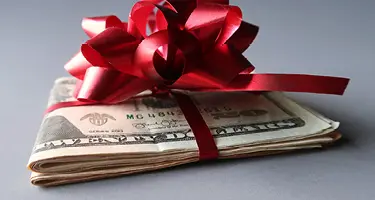 Stack of money wrapped in a festive bow, symbolizing holiday pay