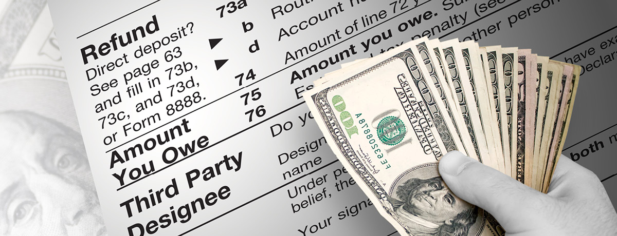 Gloved hand holding a spread of one-hundred-dollar bills near an IRS tax document 