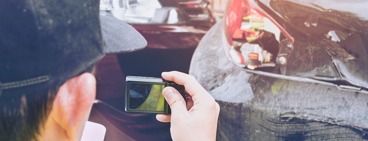 Close-up of a man taking photos of a car accident for insurance and legal purposes