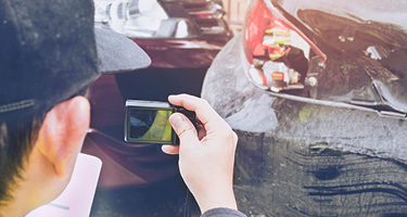 Close-up of a man taking photos of a car accident for insurance and legal purposes