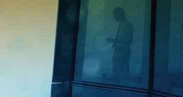Man in business suit standing in window of office building