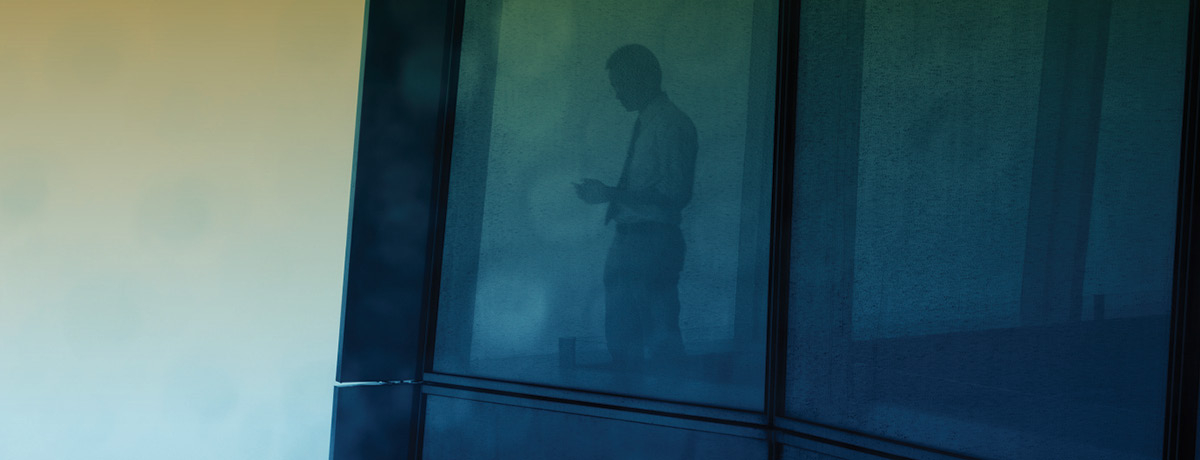 Man in business suit standing in window of office building
