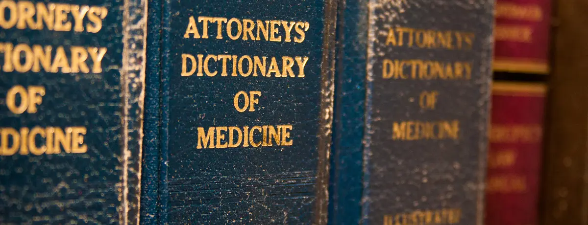 Close-up of hardcover volumes of "Attorneys' Dictionary of Medicine" with gold lettering.