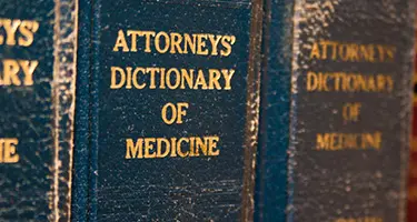 Close-up of hardcover volumes of "Attorneys' Dictionary of Medicine" with gold lettering.