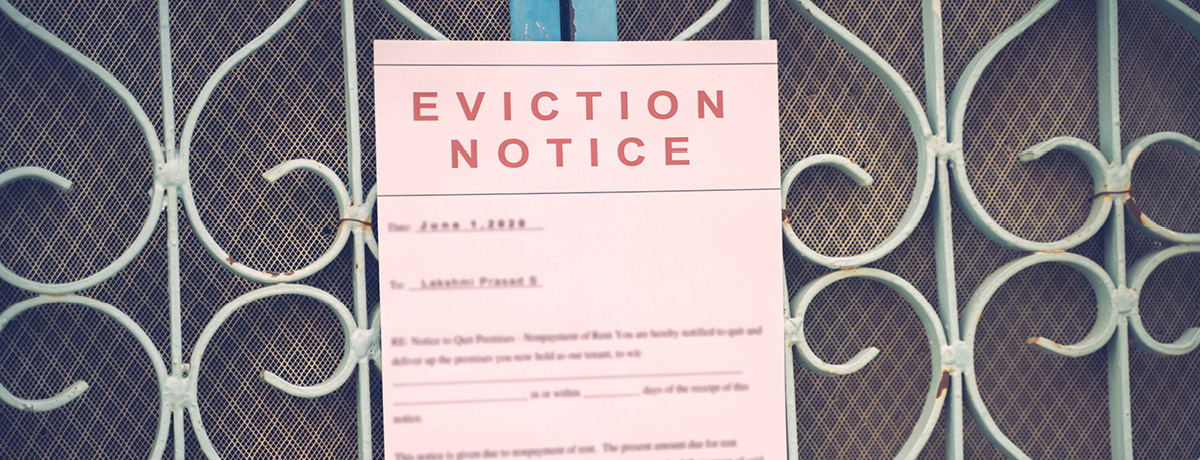 A printed eviction notice attached to a decorative metal security gate, representing housing instabi