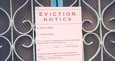 A printed eviction notice attached to a decorative metal security gate, representing housing instabi