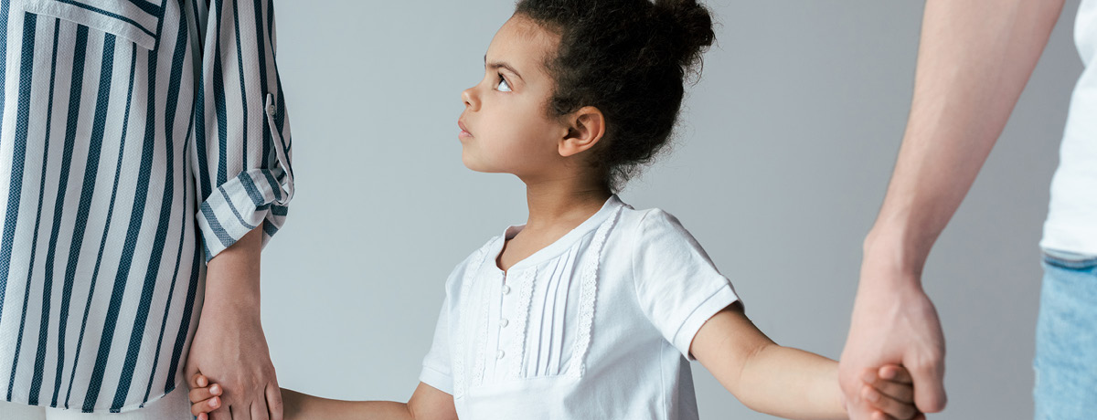 Child holding hands with two parents, symbolizing custody