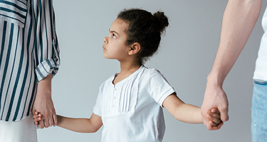Child holding hands with two parents, symbolizing custody