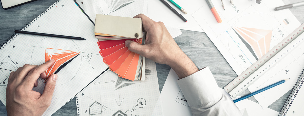 Close-up of hands using color swatches and reviewing design plans for branding