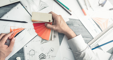 Close-up of hands using color swatches and reviewing design plans for branding