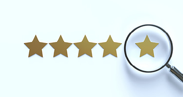 Five gold stars with a magnifying glass hovering over the right star