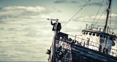 Man in suit with telescope stands on deserted boat