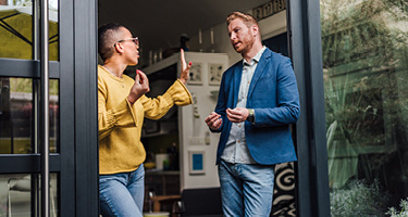 Spouses standing in doorway of home having argument