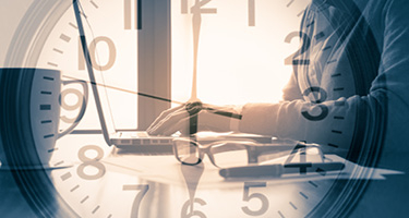 Clock over image of person typing on computer