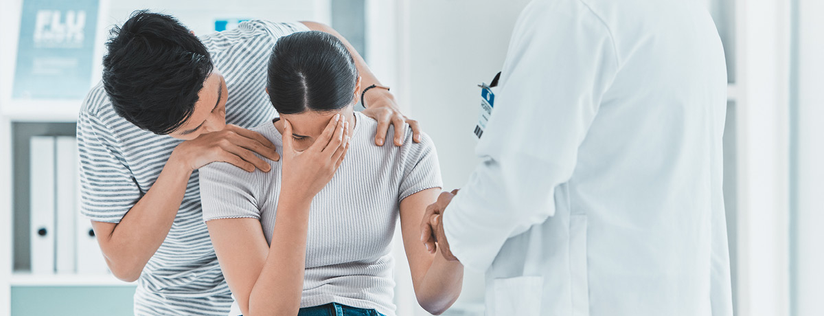 Doctor consoles couple in medical office