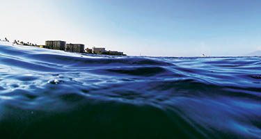 Ocean waves with buildings on shoreline