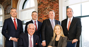 Group of lawyers seated and standing around a table
