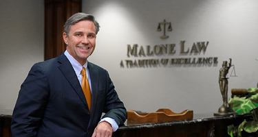 Suited man standing with arm resting on table