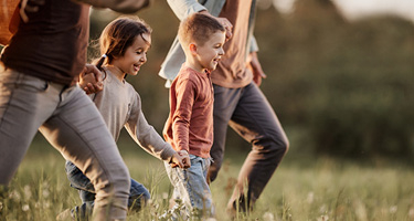 Two children in a field holding hands with parents