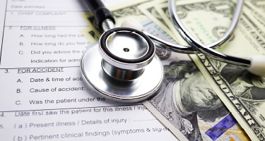 Stethoscope sitting on top of money and medical form